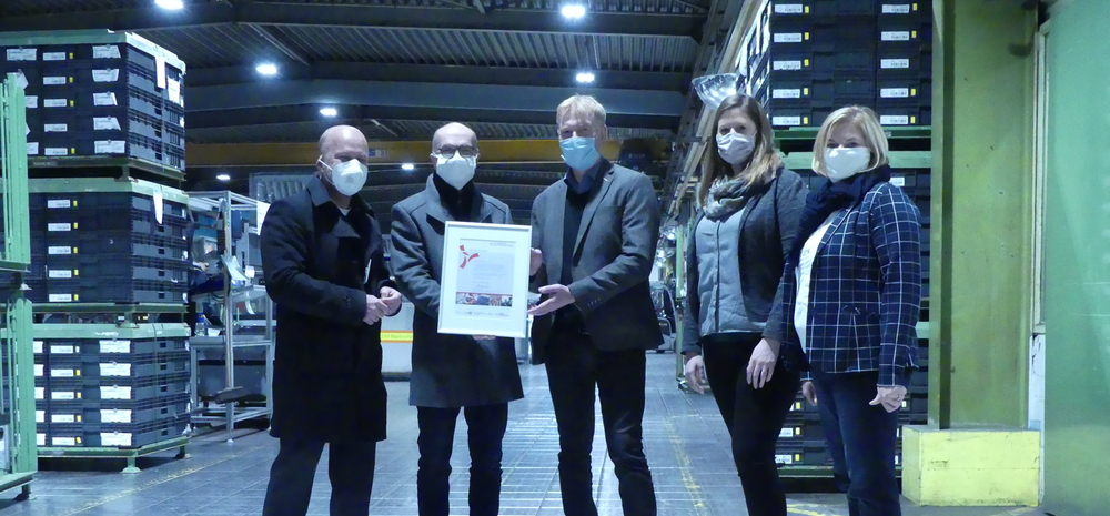 Fünf erwachsene Menschen stehen nebeneinander. Zwei der Männer halten eine Urkunde in der Hand: Die Auszeichnung Klimaschutzbertieb CO2 minus 20.